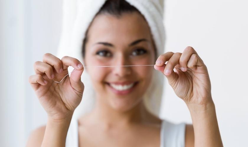 Cómo usar el hilo dental: mujer sujetando hilo.