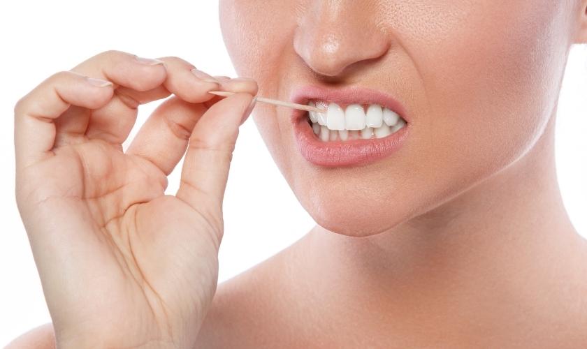 ¿Es aconsejable limpiar los dientes con palillos después de comer? | Mujer usando palillo de dientes.