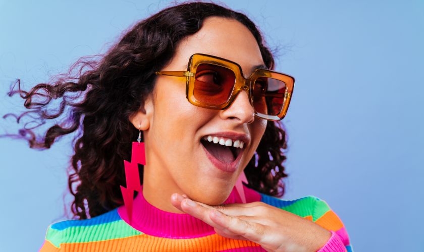 El diastema como moda, riesgos y tratamiento: mujer joven vestida con colores llamativos sonríe mostrando su diastema.