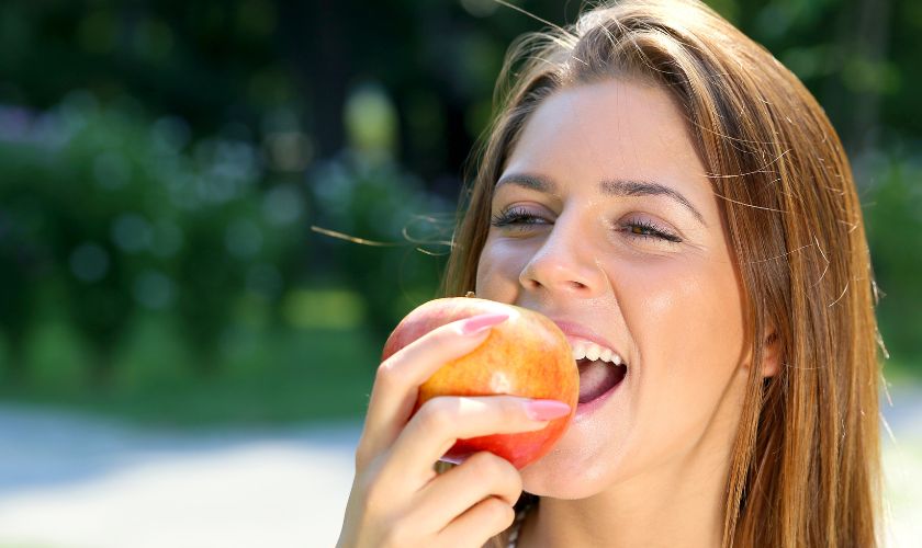 Alimentos que ayudan a prevenir y combatir la caries: mujer comiendo manzana.