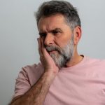 Persona con dolor dental sin caries tocándose la mandíbula