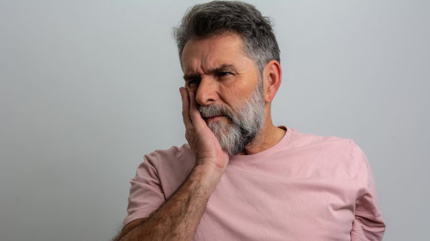 Persona con dolor dental sin caries tocándose la mandíbula